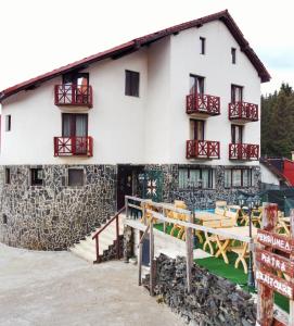 un gran edificio blanco con balcones rojos. en Pensiunea Piatra Graitoare en Vartop