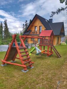 a house with three playground equipment in front of it at Apartamenty Słodyczki in Nowe Bystre