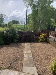 a garden with a stone wall and some flowers at Country Cabin Retreat - Hideaway & Relax in Thornhill +9 photos