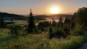 a sunset over a field with the sun in the background at Apartman JELA Jabuka in Prijepolje