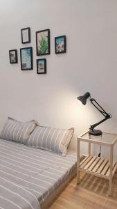 een bed met een lamp op een tafel en foto's aan de muur bij One Room in Vung Tau