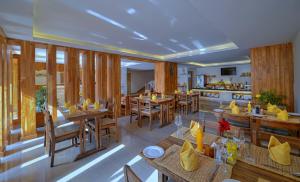 a restaurant with wooden tables and chairs and a kitchen at Aabas Pokhara by Barahi Hospitality in Pokhara