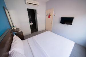 a bedroom with a white bed and a television at Golden Pearl Hotel Near Universiti Tun Hussein Onn Malaysia UTHM in Batu Pahat