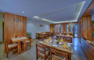 a restaurant with wooden tables and chairs and windows at Aabas Pokhara by Barahi Hospitality in Pokhara