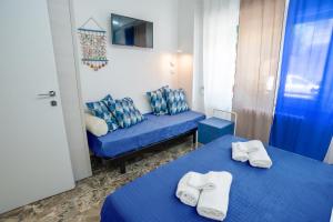 Habitación con 2 camas y sofá azul en EDEN CONERO Appartamento IL PORTO - NUMANA CENTRO, en Numana