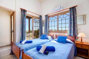 two beds in a room with two windows at Villa Katina by Villa Plus in Peyia +15 photos