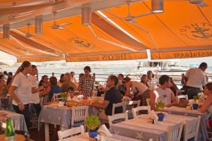 eine Gruppe von Menschen sitzt an Tischen unter einem orangefarbenen Sonnenschirm in der Unterkunft Villa Katina by Villa Plus in Peyia + 20 Fotos