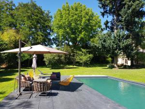 a table and chairs with an umbrella next to a pool at Le Verger Moulins Yzeure in Yzeure