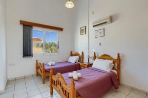 a bedroom with two beds and a window at Villa Pandora by Villa Plus in Peyia +21 photos