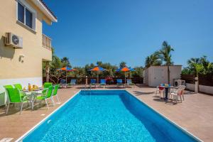 a swimming pool with a table and chairs next to a building at Villa Semeli by Villa Plus in Peyia