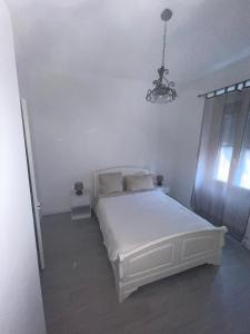 um quarto com uma cama branca e um lustre em Bel appartement pour vos séjours sur la côte em Nice