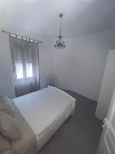 Bel appartement pour vos séjours sur la côte في نيس: غرفة نوم بيضاء فيها سرير وثريا