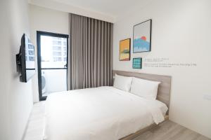 a white bedroom with a bed and a window at The Way Inn in Taichung