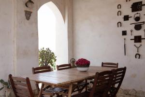 una mesa de madera con sillas y un jarrón de flores. en Casale Alma, en Marsala