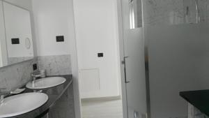 ein weißes Bad mit 2 Waschbecken und einer Dusche in der Unterkunft Casa Bonelli in Alba