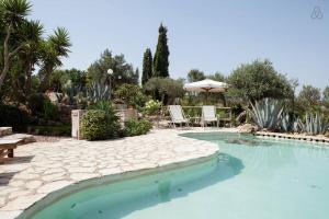 een zwembad in een tuin met een tafel en stoelen bij Casale Alma in Marsala