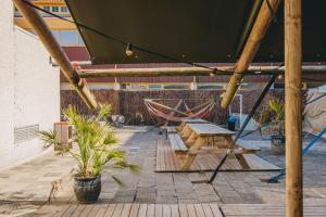 une terrasse avec une table, des hamacs et des plantes dans l'établissement Family & surfhostel, à Petten