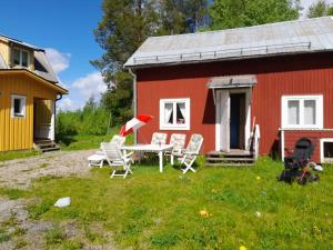a red house with chairs and a table in front of it at Summer bedroom, outside toilet, shower, kitchen. 120 m from Sandbach. in Bräcke