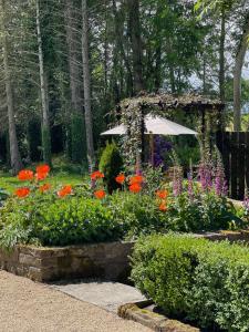 a garden with colorful flowers and an umbrella at Elm Tree Cottage in Fivemiletown +46 photos