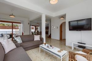 a living room with a couch and a tv at Villa Coralli by Villa Plus in Peyia