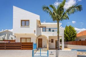 a villa with a palm tree in front of it at Villa Coralli by Villa Plus in Peyia