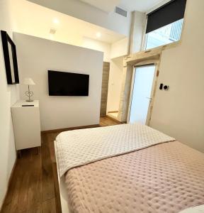 Maison ARUM - Arles, centre historique في آرل: غرفة نوم بسرير وتلفزيون بشاشة مسطحة