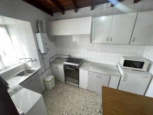 a small kitchen with a sink and a stove at Grupo Gontad Casa Baixo da Capilla Corme in A Coruña