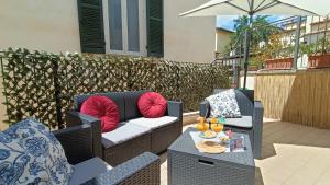 a patio with two wicker chairs and an umbrella at Cozy House con Corte Privata in Centro Storico AQ in LʼAquila