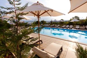 a pool at a hotel with chairs and an umbrella at Blue Waves Resort in Malinska