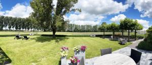 een park met stoelen en tafels en bloemen in het gras bij Hotel het Elsland in Wervik