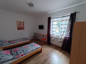 Cette chambre comprend 2 lits, une table et une fenêtre. dans l'établissement Rodinný Penzion Kyjov, à Kyjov