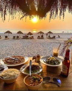 a table with plates of food on the beach at Red Rock Arambol Beach in Arambol