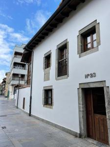 een wit gebouw met ramen aan een straat bij Apartamento del s XVI en el casco histórico de Luanco in Luanco