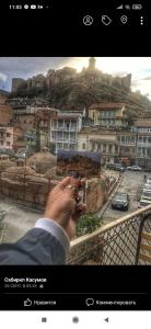 a person taking a picture of a city with their cell phone at Sabir's Apartment Old Town in Tbilisi City