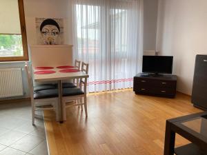 ein Wohnzimmer mit einem Tisch, Stühlen und einem TV in der Unterkunft Apartament Centrum in Iława