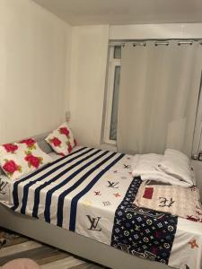 a bed with a striped blanket and a window at Belle appartement sur liège in Liège