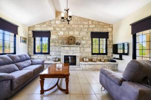 a living room with couches and a stone fireplace at Villa Theo Sapphire by Villa Plus in Lachi