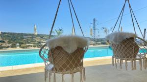 two chairs with fur on them sitting next to a swimming pool at VillaLaDiva Boutique Glamping in Massignano