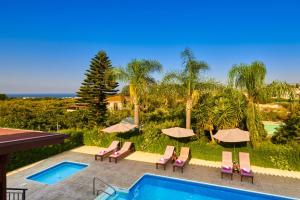 a pool with chairs and umbrellas next to a resort at Villa Yiolani by Villa Plus in Lachi