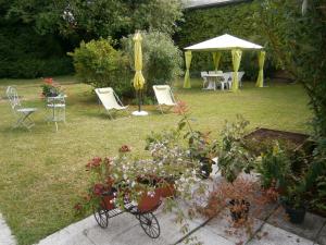 un jardín con mesa, sillas y sombrilla en Aux Sources de L'Ancre, en Miraumont