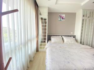 um quarto com uma cama e uma grande janela em Chic seaview @ The Patio Bangsaen em Ban Bang Saen (1)