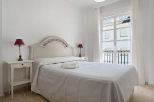a white bedroom with a white bed and a window at Casa Begines in Vejer de la Frontera +17 photos