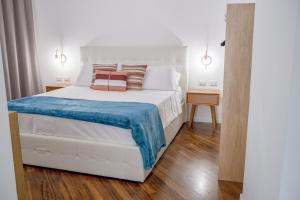 a bedroom with a white bed with a blue blanket at Castalia Apartments & Rooms Duomo Taormina in Taormina