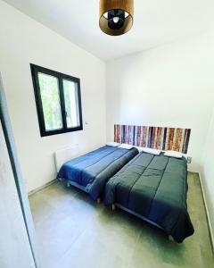 ein Schlafzimmer mit einem Bett mit blauer Decke und einem Fenster in der Unterkunft Le Photinia in Le Bugue
