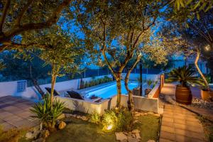 een zwembad in een achtertuin 's nachts met bomen bij Compelx with detached house and spacious apartment in Stari Grad