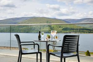 a table with two chairs and two glasses of wine at Clan Macduff Hotel in Fort William