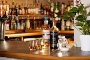 two bottles of alcohol sitting on a bar with glasses at Clan Macduff Hotel in Fort William