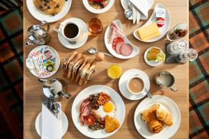 a wooden table topped with plates of breakfast food at Clan Macduff Hotel in Fort William