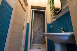 a bathroom with a sink and a shower with blue tiles at Locanda Popolare in Aci Castello