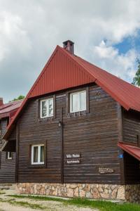 a large wooden building with a red roof at Apartments Peaks in Žabljak
